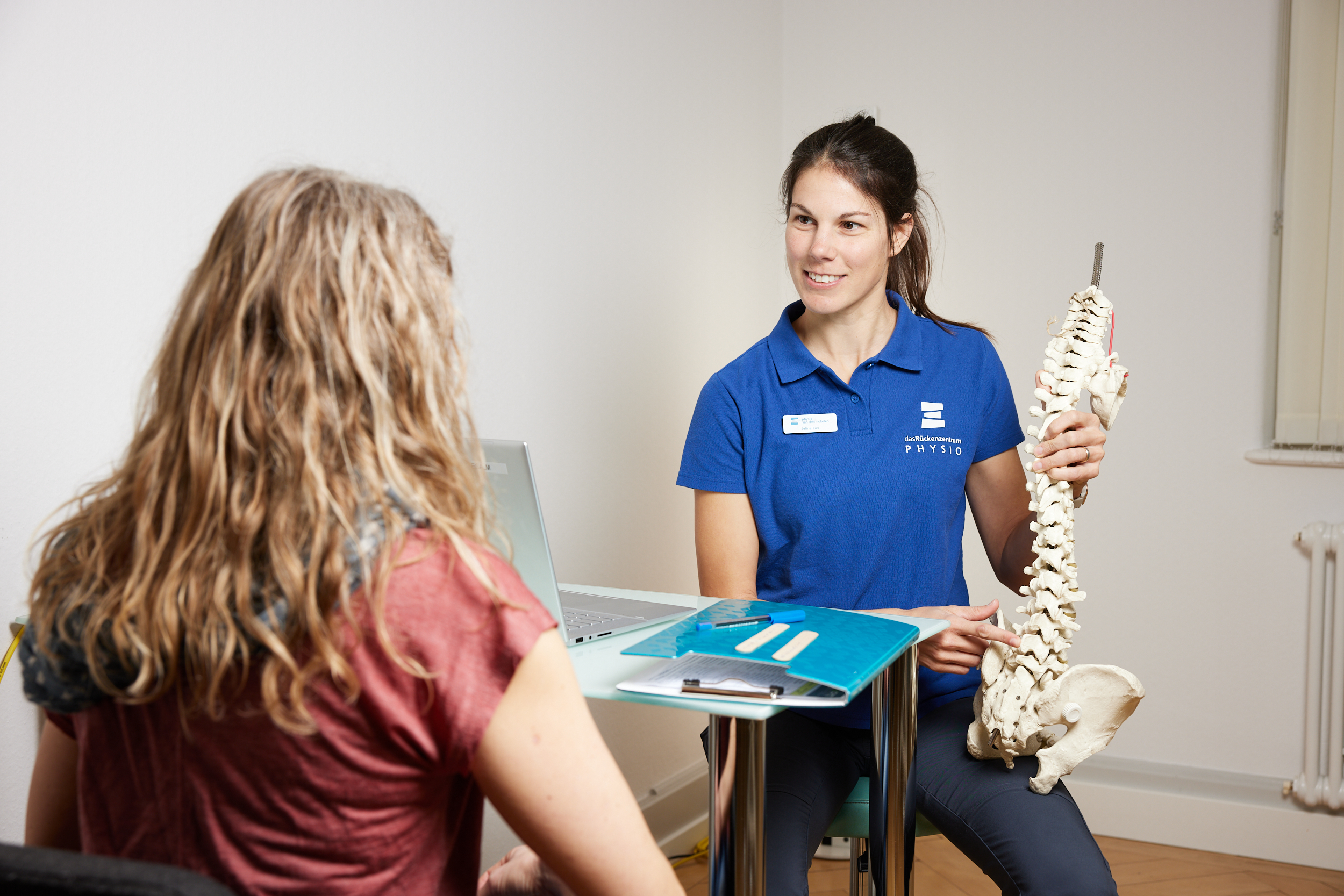 Physiotherapeut begleitet Patientin an einem Trainingsgerät